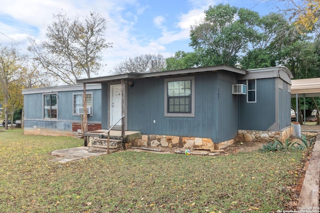 view of front of house with a wall mounted air conditioner, cooling unit, a front yard, and a carport