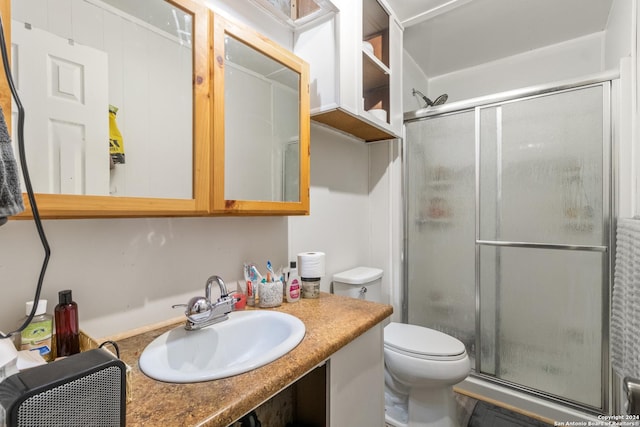 bathroom with toilet, a shower with shower door, and sink