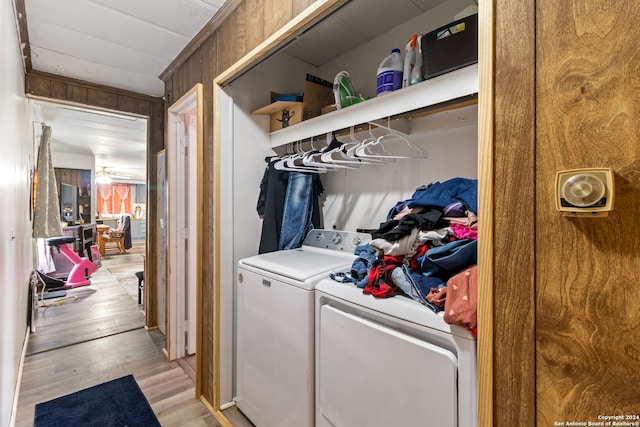 laundry area with washer and dryer, wood walls, light wood-style floors, and laundry area