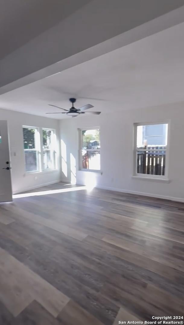 unfurnished living room featuring dark hardwood / wood-style flooring and ceiling fan