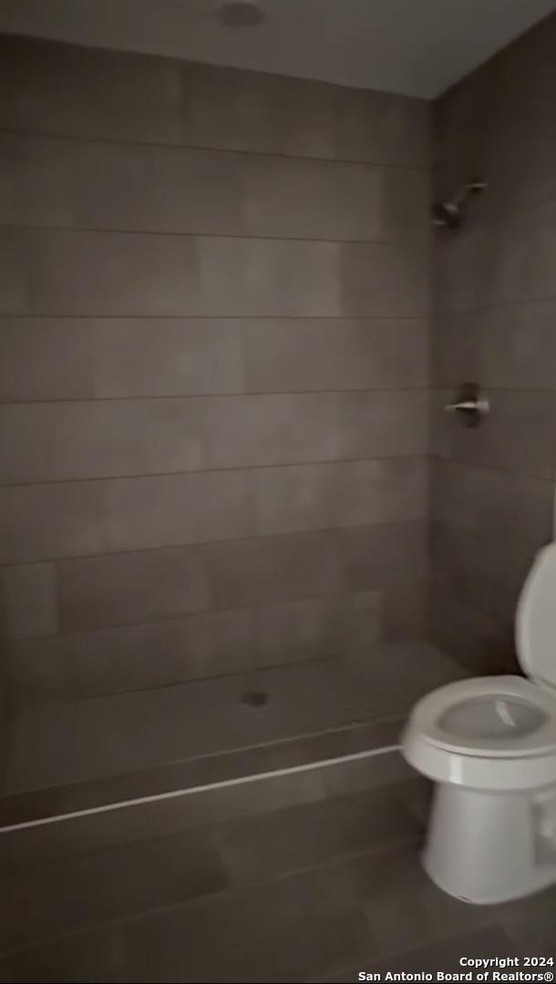 bathroom featuring a tile shower and toilet