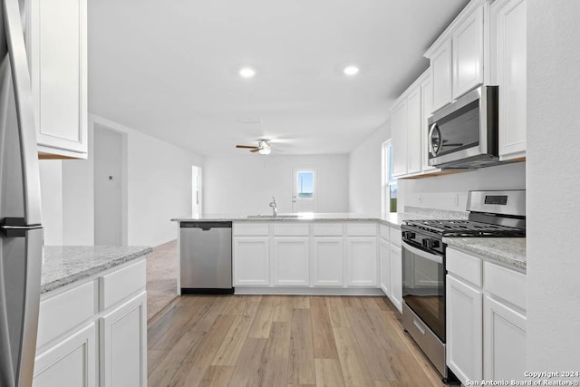 kitchen with white cabinets, stainless steel appliances, light hardwood / wood-style floors, and sink