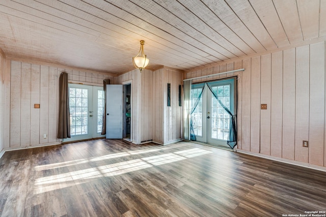 empty room with wooden walls, french doors, wooden ceiling, and hardwood / wood-style flooring