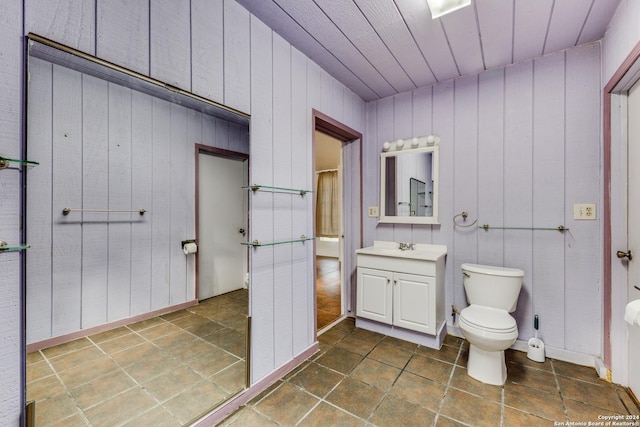 bathroom with tile patterned flooring, vanity, toilet, and wooden walls