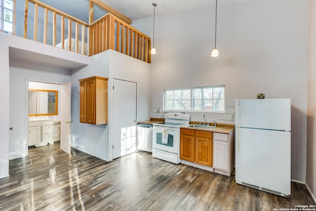 kitchen featuring sink, dark wood-type flooring, a high ceiling, decorative light fixtures, and white appliances