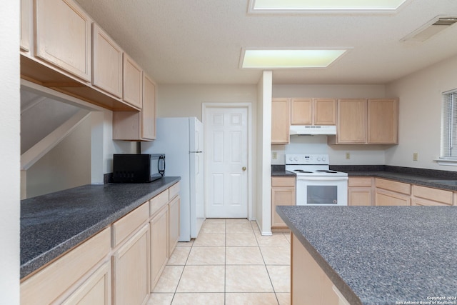 kitchen with light brown cabinetry, white appliances, a textured ceiling, and light tile patterned flooring