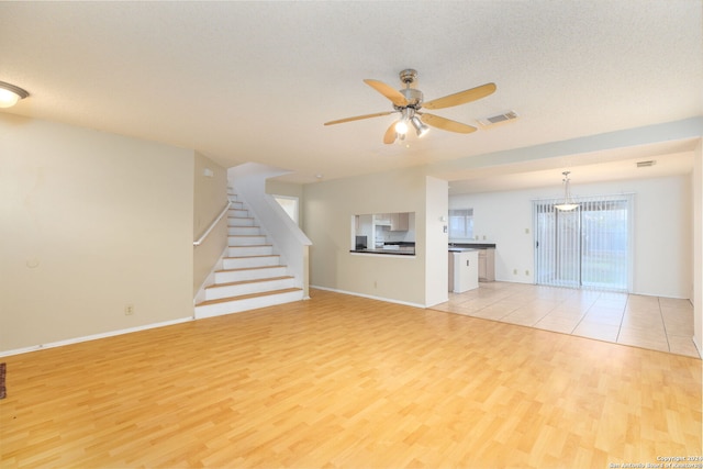 unfurnished living room with ceiling fan, light hardwood / wood-style floors, and a textured ceiling