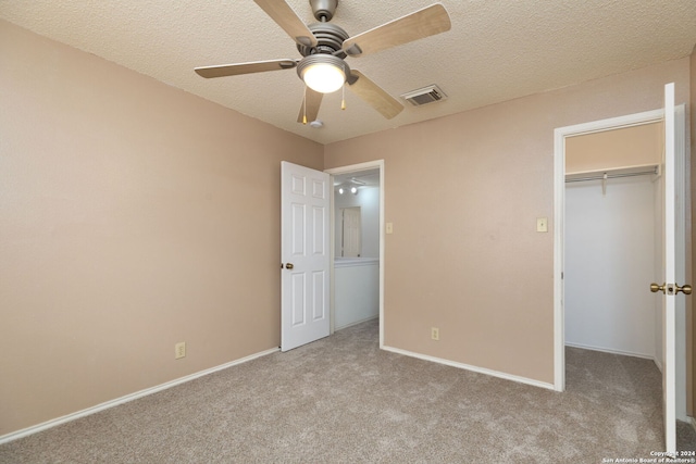 unfurnished bedroom featuring ceiling fan, light colored carpet, a textured ceiling, and a closet