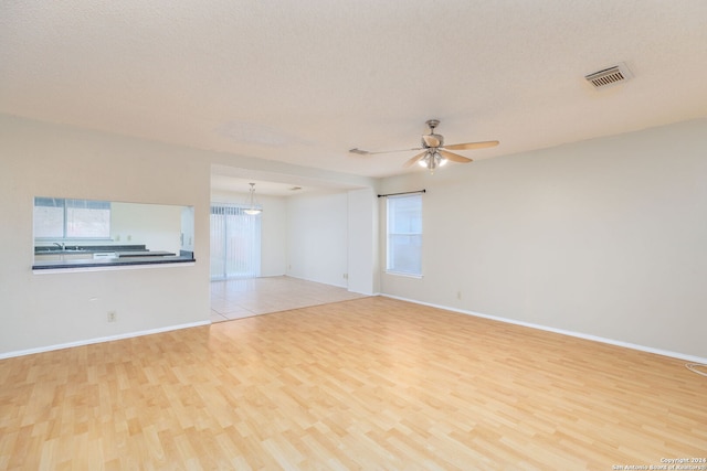 spare room featuring a textured ceiling, light hardwood / wood-style flooring, and ceiling fan