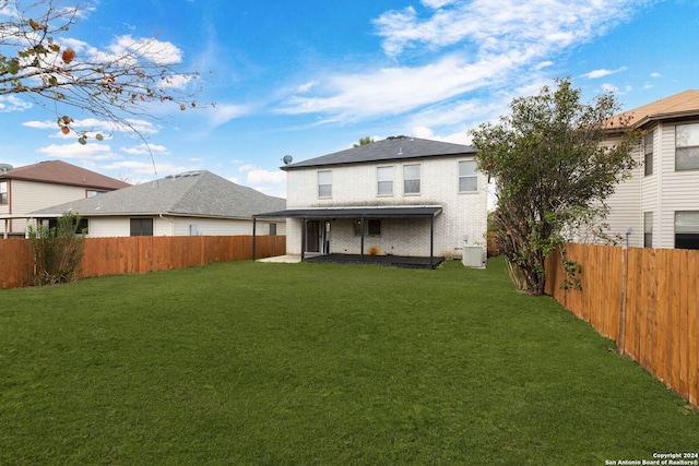 rear view of property featuring a yard and central AC unit