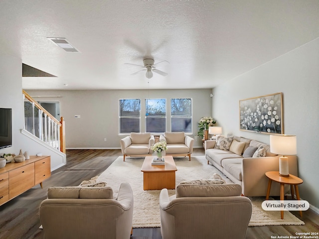 living room with a textured ceiling, ceiling fan, and dark hardwood / wood-style floors