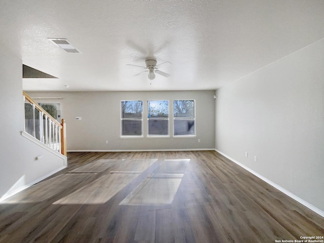 unfurnished living room featuring ceiling fan, dark wood-type flooring, and a textured ceiling