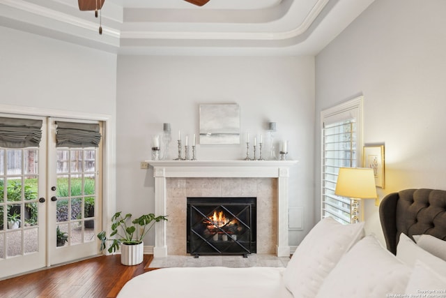 living room featuring a tiled fireplace, hardwood / wood-style flooring, and a tray ceiling