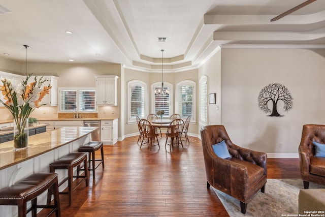 dining space with dark wood-type flooring, a raised ceiling, and a notable chandelier