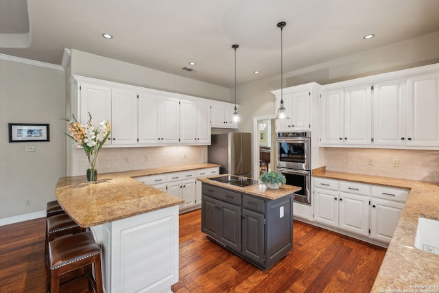 kitchen featuring stainless steel appliances, white cabinetry, a center island, and light stone counters