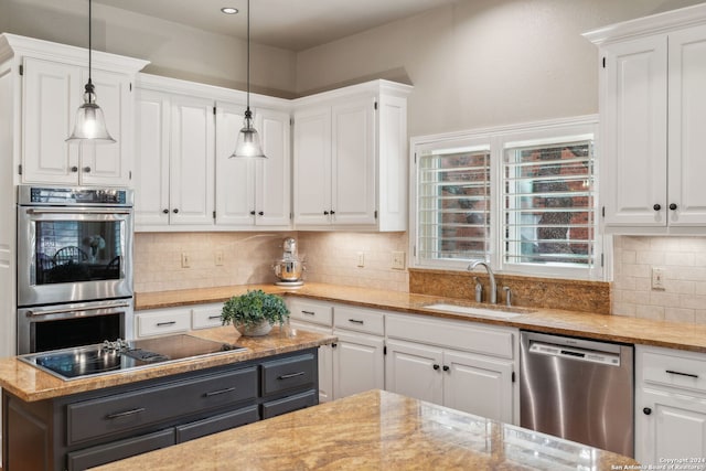 kitchen featuring white cabinetry, stainless steel appliances, decorative light fixtures, and sink