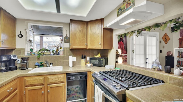 kitchen with decorative backsplash, kitchen peninsula, extractor fan, sink, and black appliances