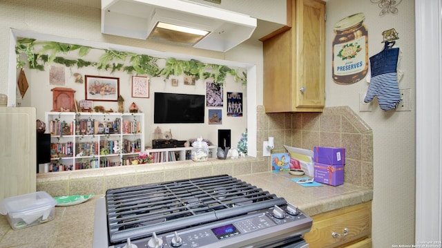 kitchen featuring light brown cabinets, backsplash, and stainless steel stove