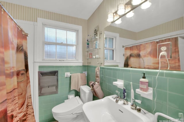 bathroom with a shower with curtain, sink, tile walls, and toilet