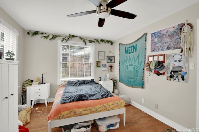 bedroom featuring ceiling fan, wood-type flooring, and multiple windows