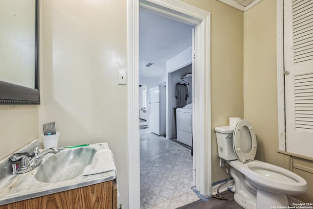 bathroom featuring toilet, washer / dryer, and vanity