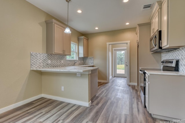 kitchen with kitchen peninsula, stainless steel appliances, a healthy amount of sunlight, and light hardwood / wood-style floors