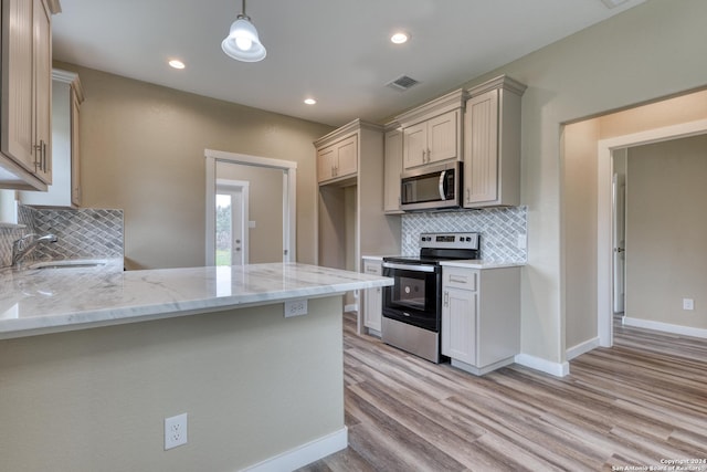 kitchen with sink, tasteful backsplash, light hardwood / wood-style flooring, pendant lighting, and appliances with stainless steel finishes