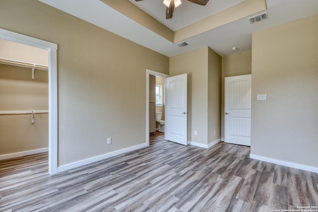 unfurnished bedroom featuring ceiling fan, a closet, a spacious closet, and light hardwood / wood-style flooring