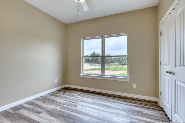 empty room with ceiling fan, a healthy amount of sunlight, and light wood-type flooring