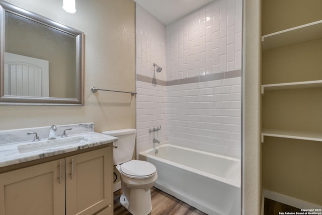 full bathroom with hardwood / wood-style floors, vanity, tiled shower / bath combo, and toilet