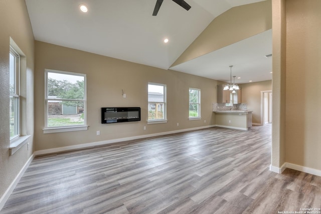 unfurnished living room featuring ceiling fan with notable chandelier, light hardwood / wood-style floors, and lofted ceiling