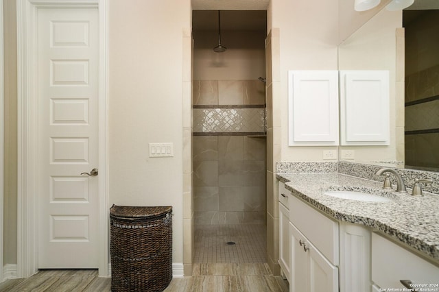 bathroom featuring hardwood / wood-style flooring, vanity, and tiled shower