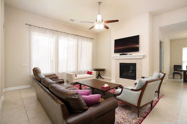 living room featuring a tile fireplace, ceiling fan, and light tile patterned flooring