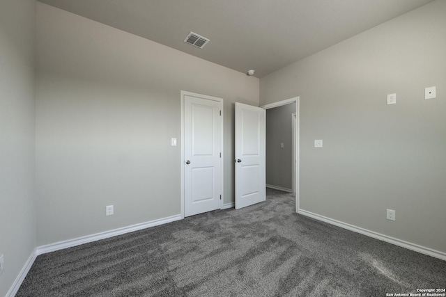 unfurnished bedroom with dark colored carpet