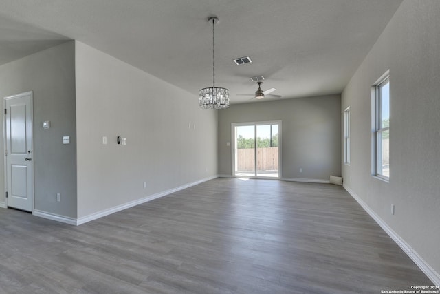 unfurnished room with a textured ceiling, hardwood / wood-style floors, and ceiling fan with notable chandelier