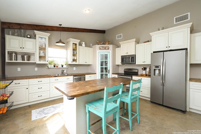 kitchen featuring decorative light fixtures, white cabinetry, sink, and appliances with stainless steel finishes