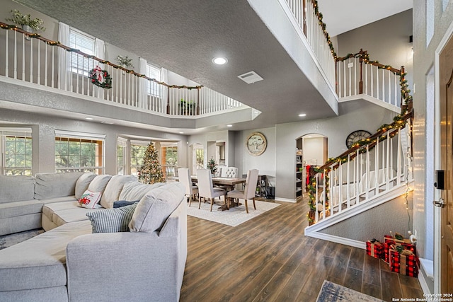 living room with dark hardwood / wood-style floors, a towering ceiling, and a textured ceiling