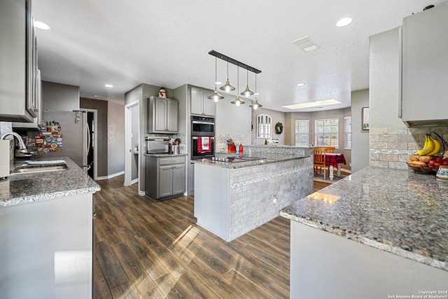 kitchen with gray cabinetry, decorative light fixtures, sink, and dark wood-type flooring