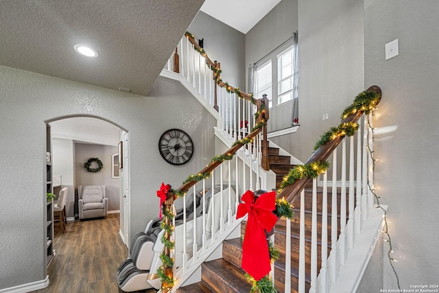 stairway with a textured ceiling and hardwood / wood-style flooring