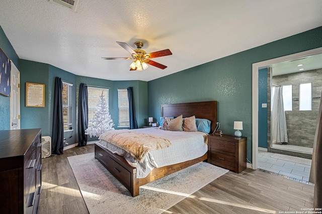 bedroom with hardwood / wood-style floors, a textured ceiling, ceiling fan, and connected bathroom