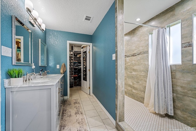 bathroom with tile patterned floors, curtained shower, a healthy amount of sunlight, and a textured ceiling