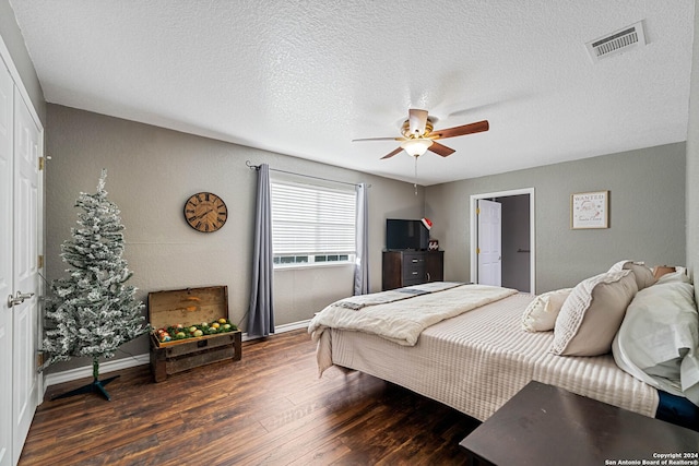 bedroom featuring a textured ceiling, a closet, ceiling fan, and dark wood-type flooring