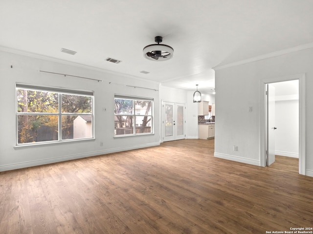 unfurnished living room with a chandelier, wood-type flooring, and ornamental molding