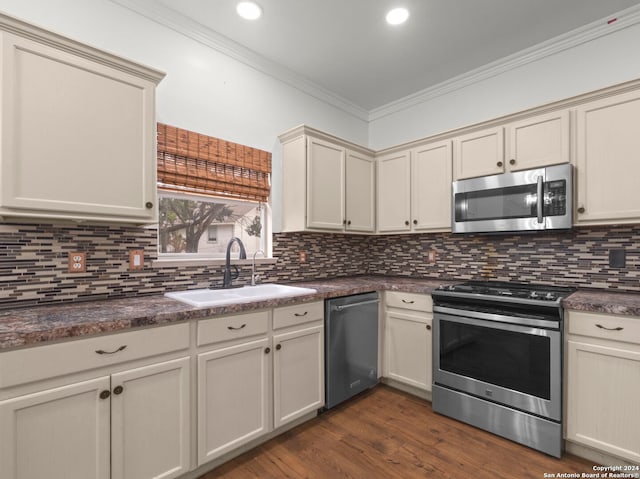 kitchen with sink, dark wood-type flooring, tasteful backsplash, cream cabinetry, and appliances with stainless steel finishes