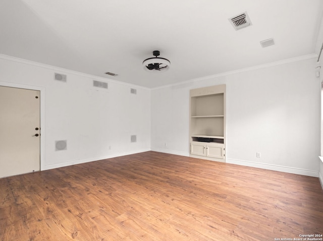 spare room with crown molding, hardwood / wood-style floors, and built in features