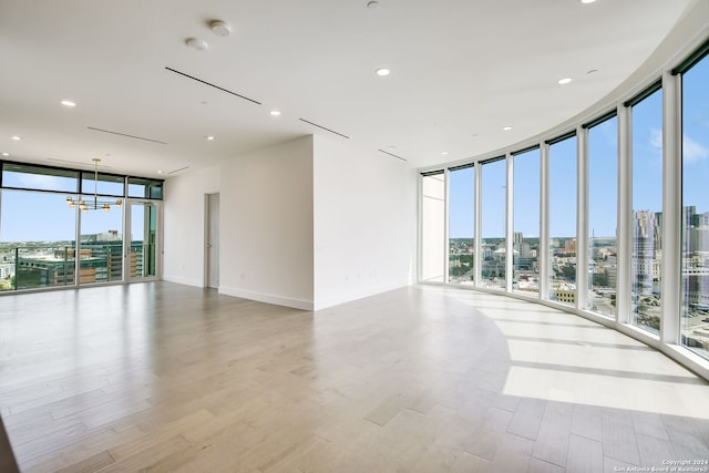 unfurnished room with a chandelier, light hardwood / wood-style flooring, and expansive windows