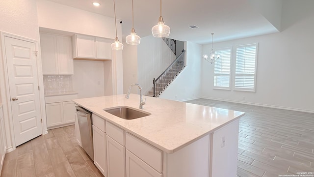 kitchen featuring light stone countertops, dishwasher, sink, a center island with sink, and white cabinets