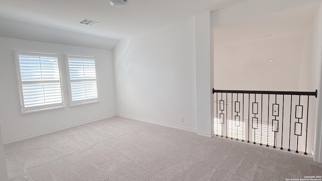 empty room with light colored carpet and vaulted ceiling