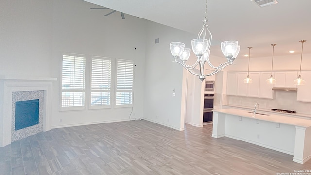 kitchen with stainless steel microwave, sink, pendant lighting, a breakfast bar, and white cabinets