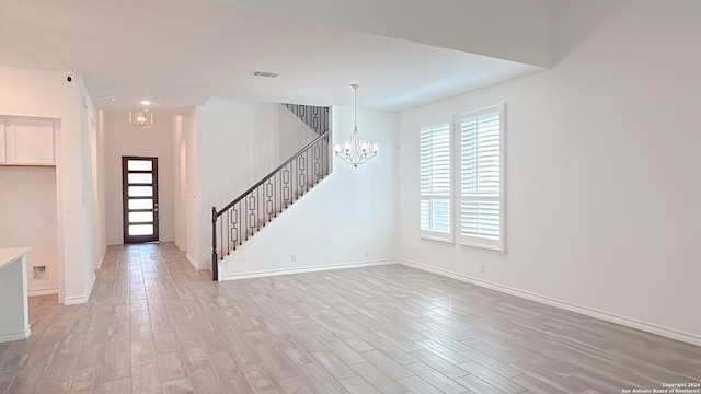 unfurnished living room featuring wood-type flooring and a notable chandelier